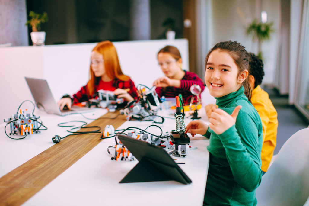 diverse group of children working together on computers in a modern classroom setting. (1)